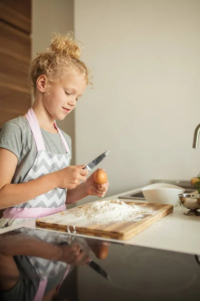 Niña de pie en la cosecha madre y romper el huevo a la harina en la cocina. —  Fotos de Stock