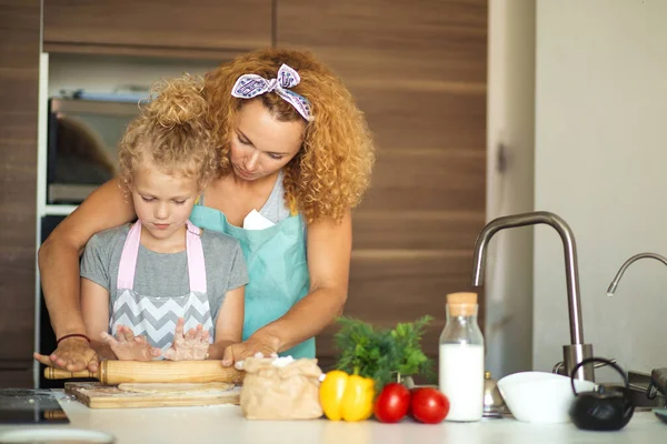 Piękna młoda mama i jej urocza córeczka bawią się i uśmiechają podczas pieczenia w kuchni w domu — Zdjęcie stockowe