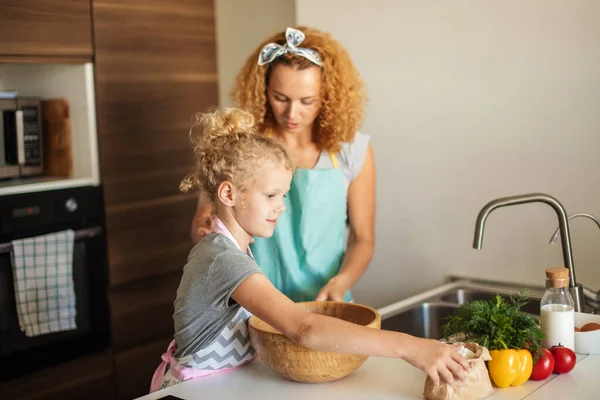 Attraktive junge Frau und ihre kleine süße Tochter kochen in der Küche. — Stockfoto