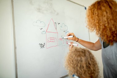 Annesi keçeli kalemle gemide yazan küçük bir kız. Öğrenim ve okul kavramı.