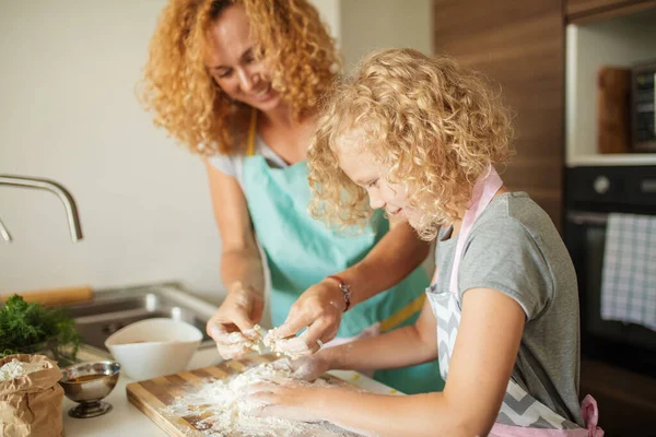 Donna e figlia carina che cucina in cucina, facendo pasta per la festa di compleanno. — Foto Stock