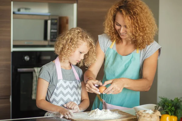 Mujer y linda hija cocinando en la cocina, haciendo masa para la fiesta de cumpleaños. — Foto de Stock