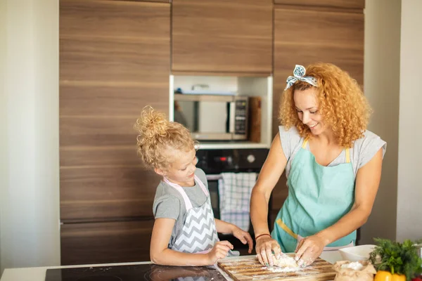 Γυναίκα και χαριτωμένη κόρη μαγειρεύουν στην κουζίνα, κάνοντας τα χρήματα για το πάρτι γενεθλίων. — Φωτογραφία Αρχείου