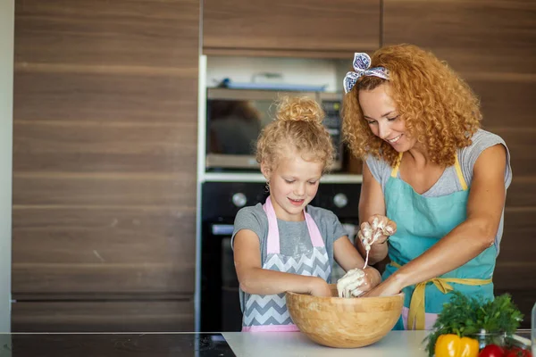 台所で夕食を作りながら楽しい時間を過ごしている母親と子供の娘. — ストック写真
