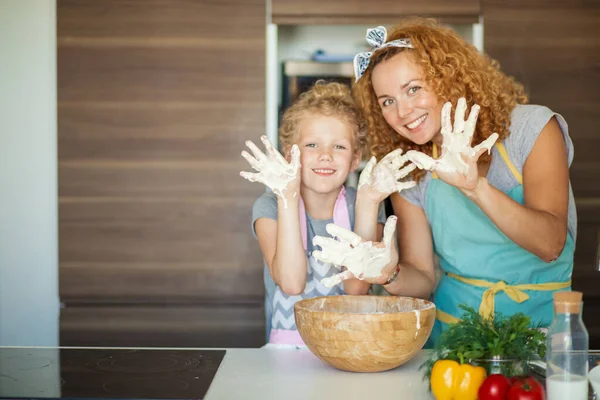 Mother and child daughter girl having fun while making dinner at the kitchen.