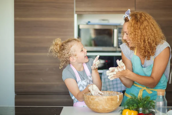 台所で夕食を作りながら楽しい時間を過ごしている母親と子供の娘. — ストック写真
