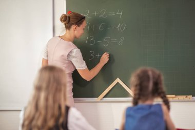 Öğretmenim derste beyaz tahtada duruyor.