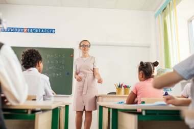 Öğretmen okulda çocuklara ödevlerinde yardım ediyor.