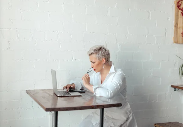 미소짓는 사업가가 책상에 앉아서 노트북을 가지고 사업에 대해 생각하고 있습니다 — 스톡 사진