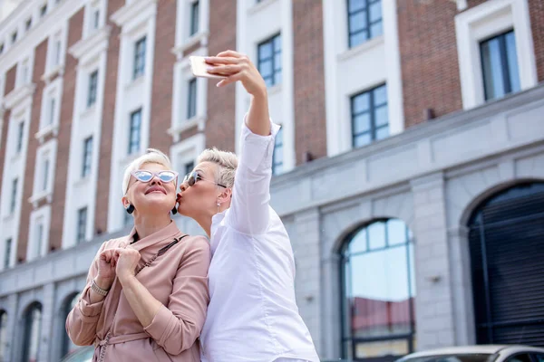 Mujeres de negocios adultos elegantes posan para selfie afuera cerca del edificio de oficinas — Foto de Stock