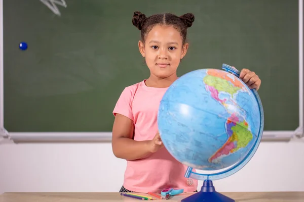 African schoolgirl looking globe with chalk background — стоковое фото