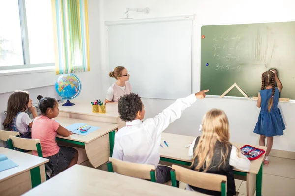 Escolar con maestro en el aula. Chica cerca de pizarra mostrar su tarea —  Fotos de Stock