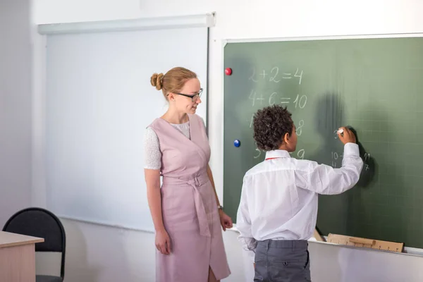 Pojklösning tillägg och subtraktion ombord. skolpojke skriva lösning av matematisk operation — Stockfoto