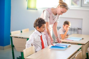 Öğretmen okulda çocuklara ödevlerinde yardım ediyor.