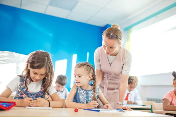 Lärare hjälper barn med läxorna i klassrummet i skolan — Stockfoto