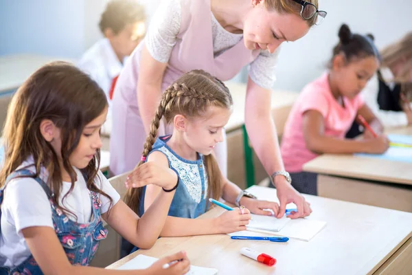 Profesor ayudando a los niños con su tarea en el aula de la escuela —  Fotos de Stock