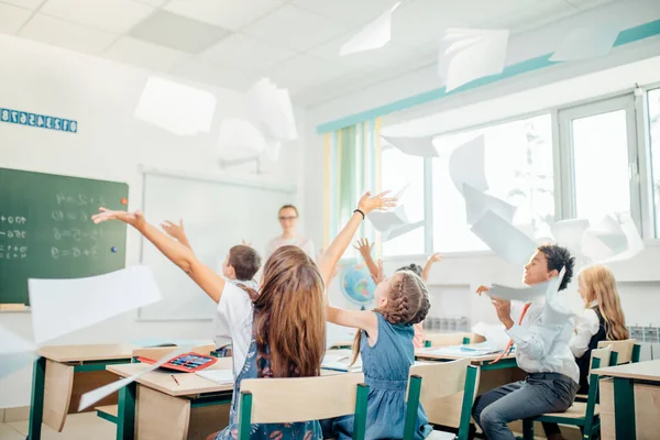 Dzieci w szkole bawić się w klasie i rzucanie papieru w powietrzu — Zdjęcie stockowe
