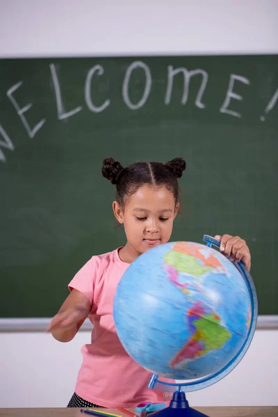 African schoolgirl looking globe with chalk background — стоковое фото