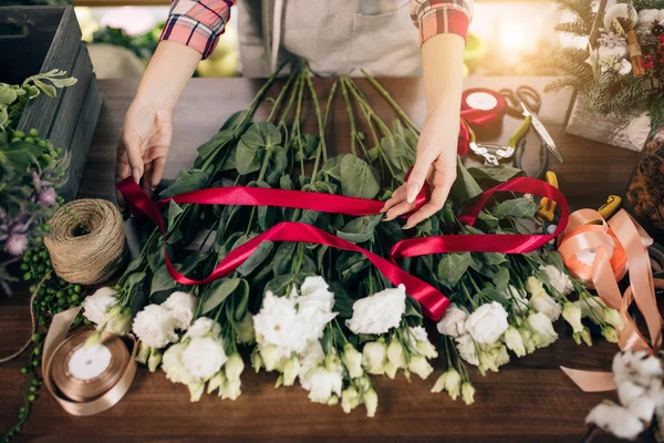 florist woman tie bouquet of flowers with ribbon