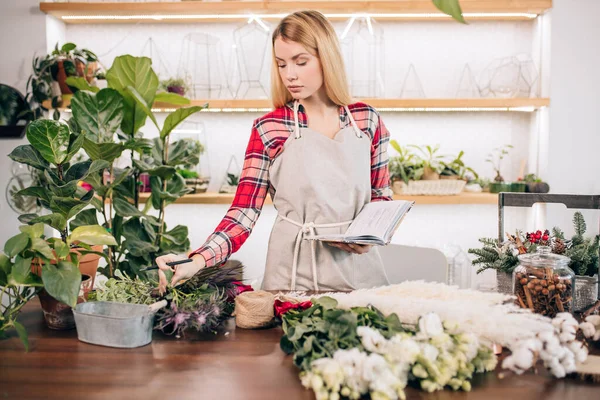 Young lady florist make notes at work — Stock Photo, Image