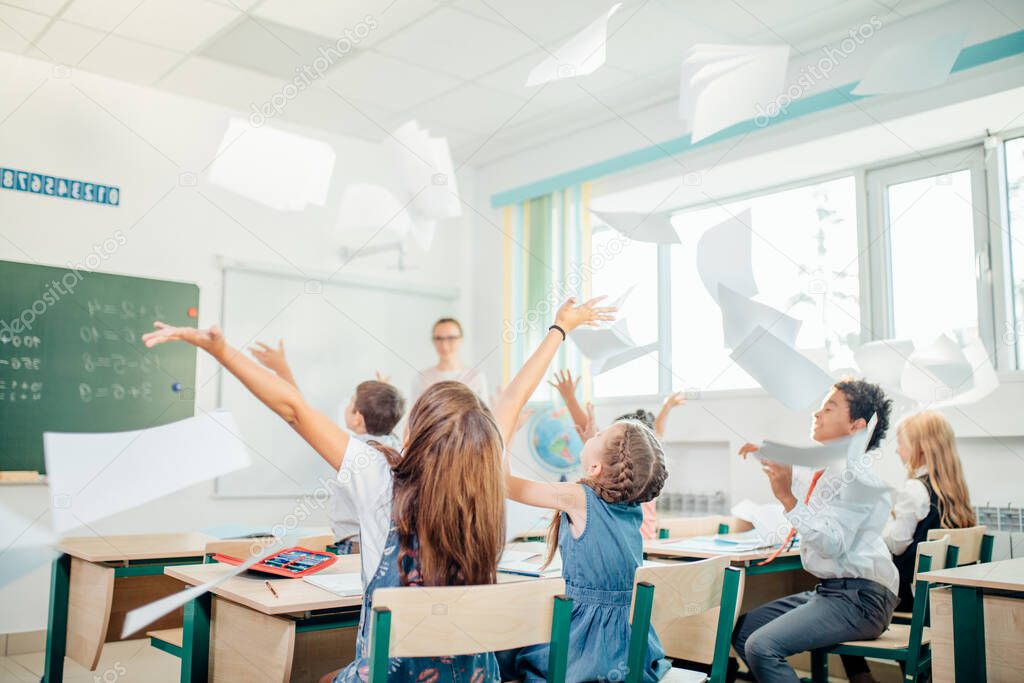 school kids have fun in class and throwing paper in air
