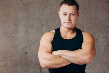 Genç kendine güvenen güçlü sporcu kollarını kavuşturmuş duruyor.