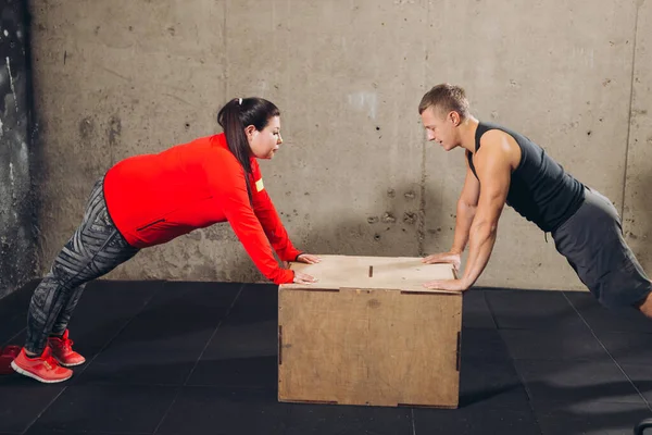Sportos férfi és kövér nő támaszkodik a dobozra, és edz — Stock Fotó