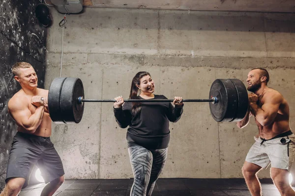 Twee mannen en overgewicht meisje training met lange halter — Stockfoto