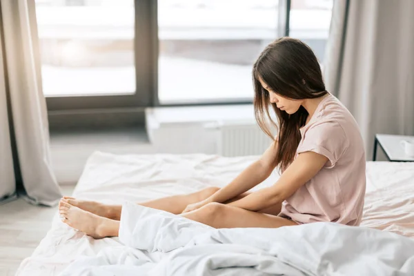 Deprimida jovem ressentida mulher sentada na cama — Fotografia de Stock