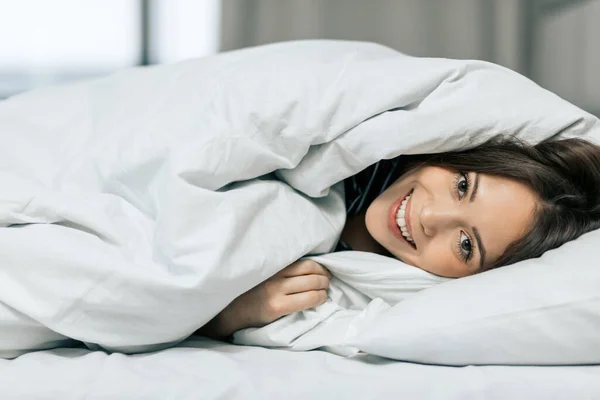 Позитивная симпатичная женщина, наслаждающаяся лежанием в кровати — стоковое фото