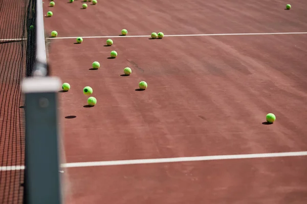 Röd-lera tennisbana med sportutrustning och tennisbollar på den. — Stockfoto