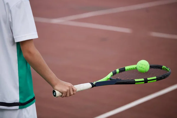 Close-up van de mannelijke hand houden tennisbal en racket op rood-klei baan. — Stockfoto