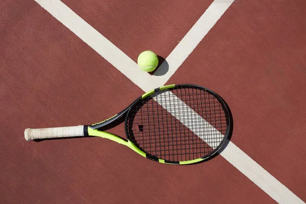 Raqueta de tenis y pelota en un fondo de pista de tenis de arcilla roja — Foto de Stock