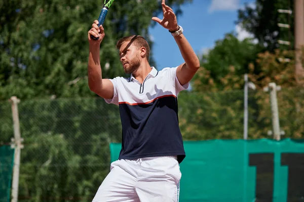 Joven en ropa deportiva está jugando al tenis en la pista de al aire libre. — Foto de Stock