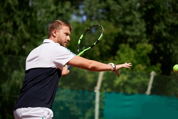 Jeune homme en vêtements de sport joue au tennis sur le court de porte. — Photo