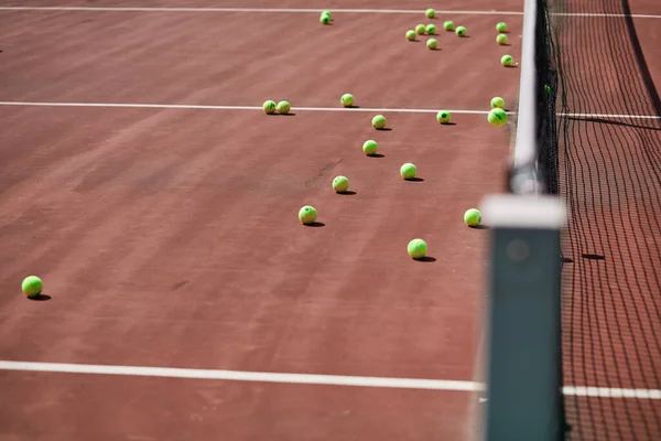 Röd-lera tennisbana med sportutrustning och tennisbollar på den. — Stockfoto