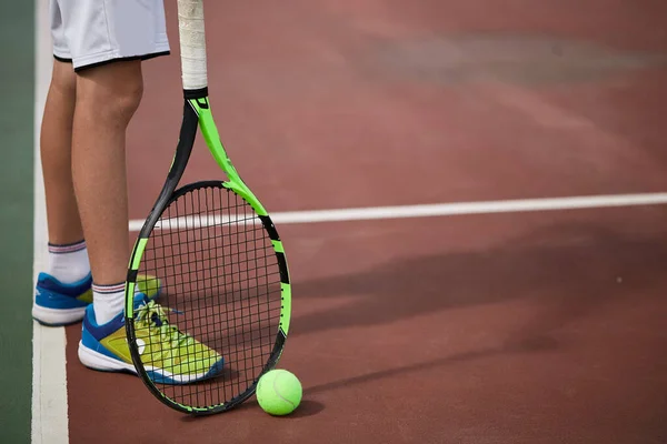 Erkek eli kırmızı kil kortta tenis topu ve raket tutuyor.. — Stok fotoğraf