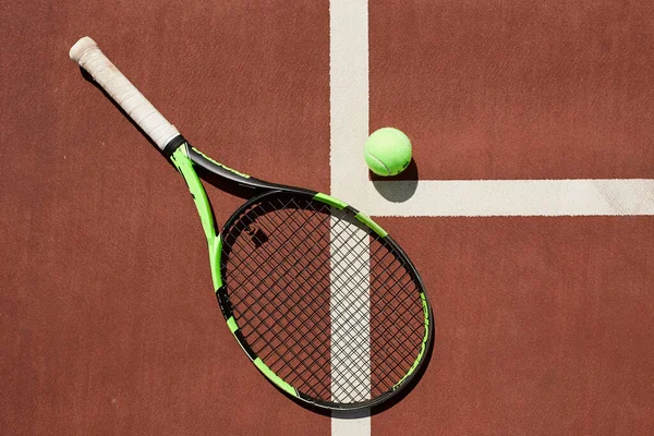 Tennisracket en bal op een rode klei tennisbaan achtergrond — Stockfoto