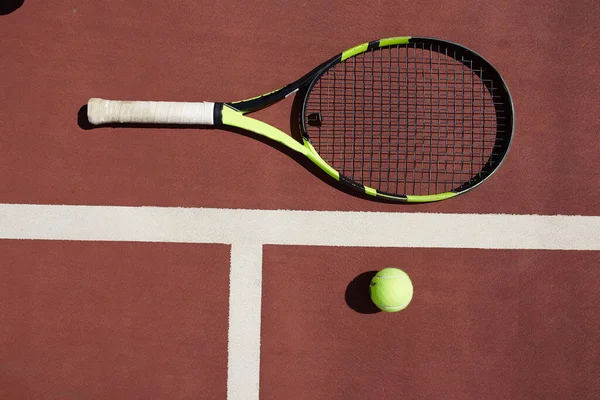 Raqueta de tenis y pelota en un fondo de pista de tenis de arcilla roja — Foto de Stock