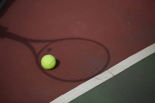 Raqueta de tenis y pelota en un fondo de pista de tenis de arcilla roja — Foto de Stock