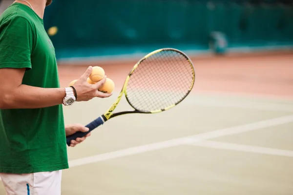 Hombre barbudo joven en ropa deportiva verde está jugando al tenis en la cancha cubierta. —  Fotos de Stock
