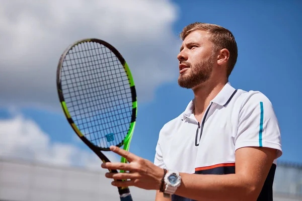 Jeune homme en vêtements de sport joue au tennis sur le court de porte. — Photo