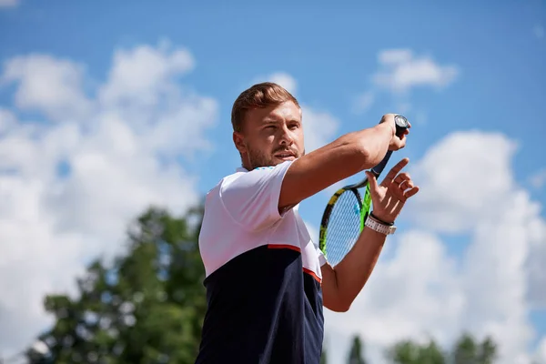 Joven en ropa deportiva está jugando al tenis en la pista de al aire libre. —  Fotos de Stock