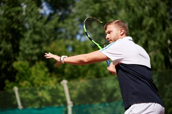 Junger Mann in Sportbekleidung spielt Tennis auf Außenplatz. — Stockfoto