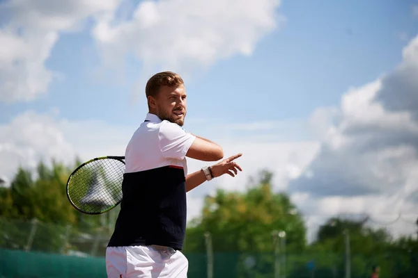 Junger Mann in Sportbekleidung spielt Tennis auf Außenplatz. — Stockfoto