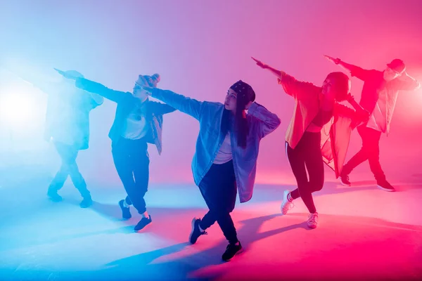 Diverso grupo de personas bailando en estudio con luz de doble color roja y azul —  Fotos de Stock