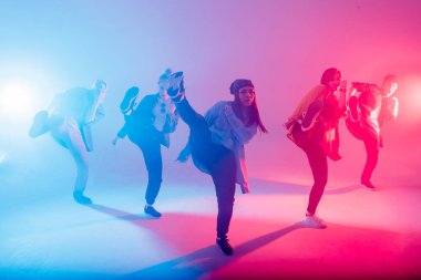 Group of diverse young hip-hop dancers in studio with special lighting effects clipart