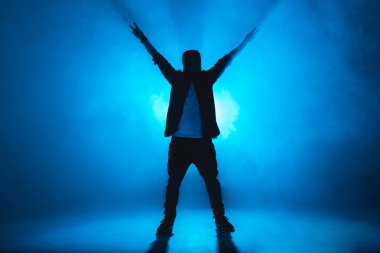 Modern tarz hip-hop dansçısı dansını mavi stüdyo arka planında gösteriyor..