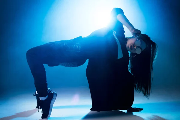 Mujer joven bailarina de hip-hop en el estudio fondo de luz azul con efectos de bengala —  Fotos de Stock