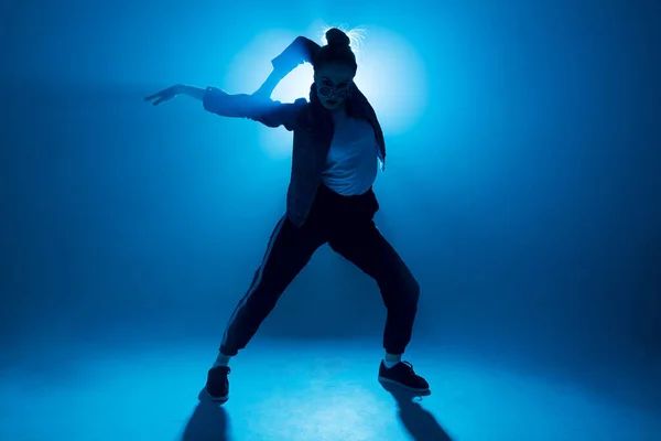 Joven bailarina de hip-hop actuando en solitario en el escenario con luces azules de neón —  Fotos de Stock